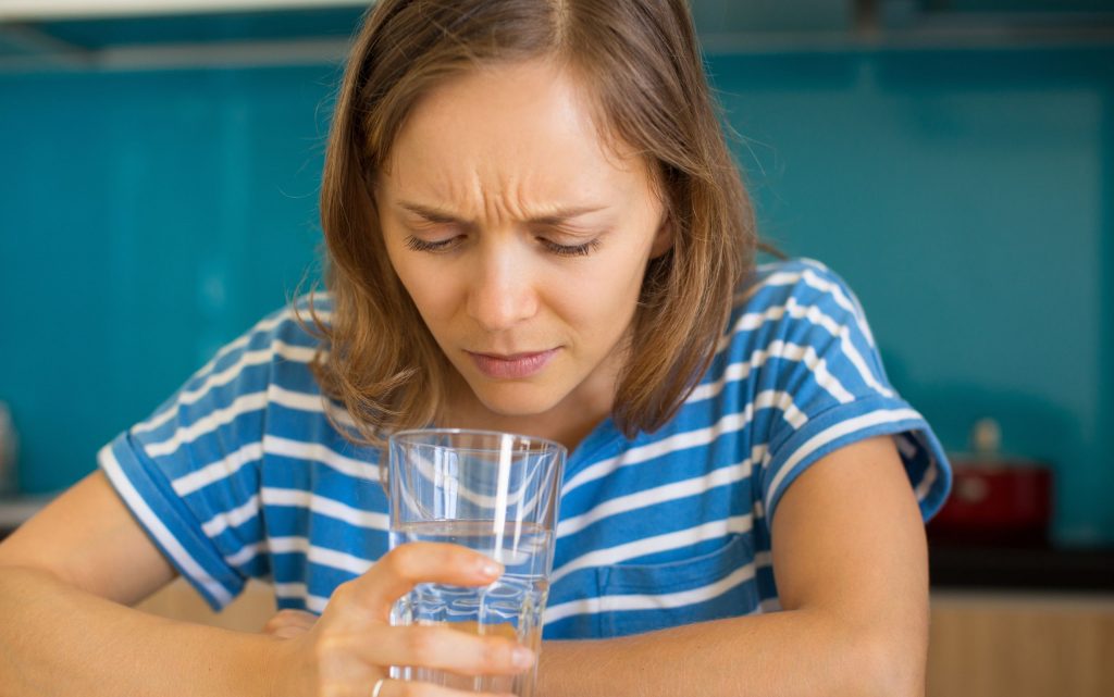 Bild: Frau schaut verunsichert in ein Wasserglas. Unterschrift: Kann ich mein Trinkwasser trotz Abkochgebot bedenkenlos trinken?